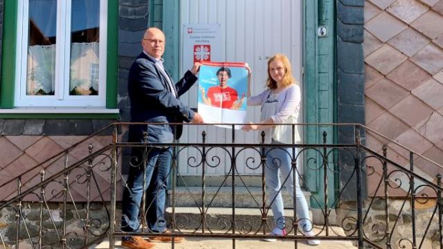 Michael Seifert und Tina Hallemann zeigen das Plakat zur Aktionswoche Schuldnerberatung 2022 vor dem Caritas-Centrum in Herzberg am Harz. | Foto: Caritas