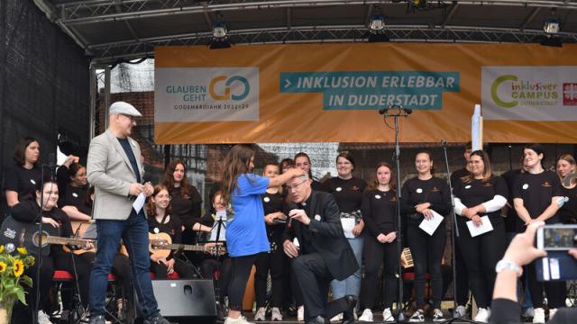 Die Viertklässlerin, die im Video als Aribo die Weihe vollzog, bat Bischof Heiner Wilmer auf die Bühne, um ihm als „Bischöfin Adeleida“ zu demonstrieren, wie die Weihe damals durch Handauflegen erfolgte. | Foto: Iris Blank