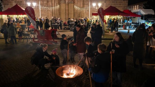 Das Foto zeigt im Vordergrund die Feuerschale zum Stockbrotbacken, im Hintergrund den Haupteingang der Basilika.